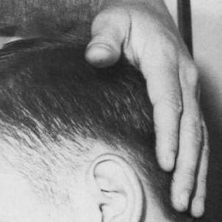 A hand resting on the back of a man's head