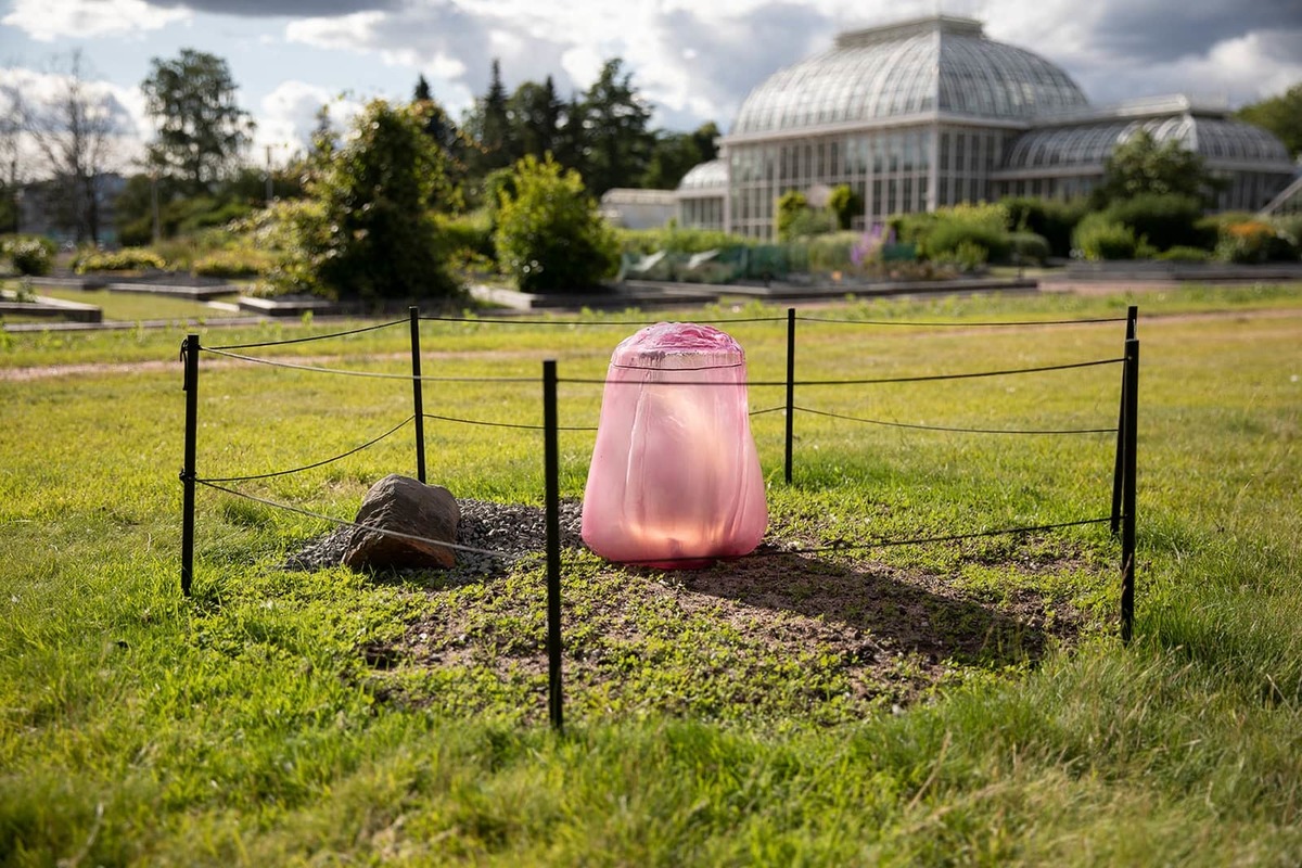 A pink glass chamber surrounded be a small rope fence